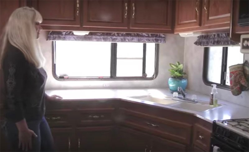 Unutrašnjost kampa sa kamp prikolicom gde par živi van mreže